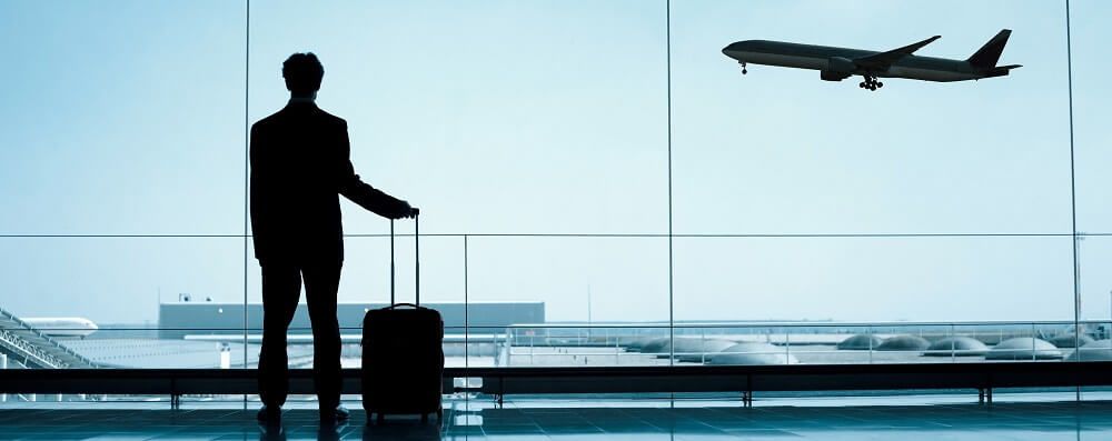 Businessman looking out at planes in airport | Learn Tips to Prepare For Culture Shock When Moving Overseas | AW Transportation